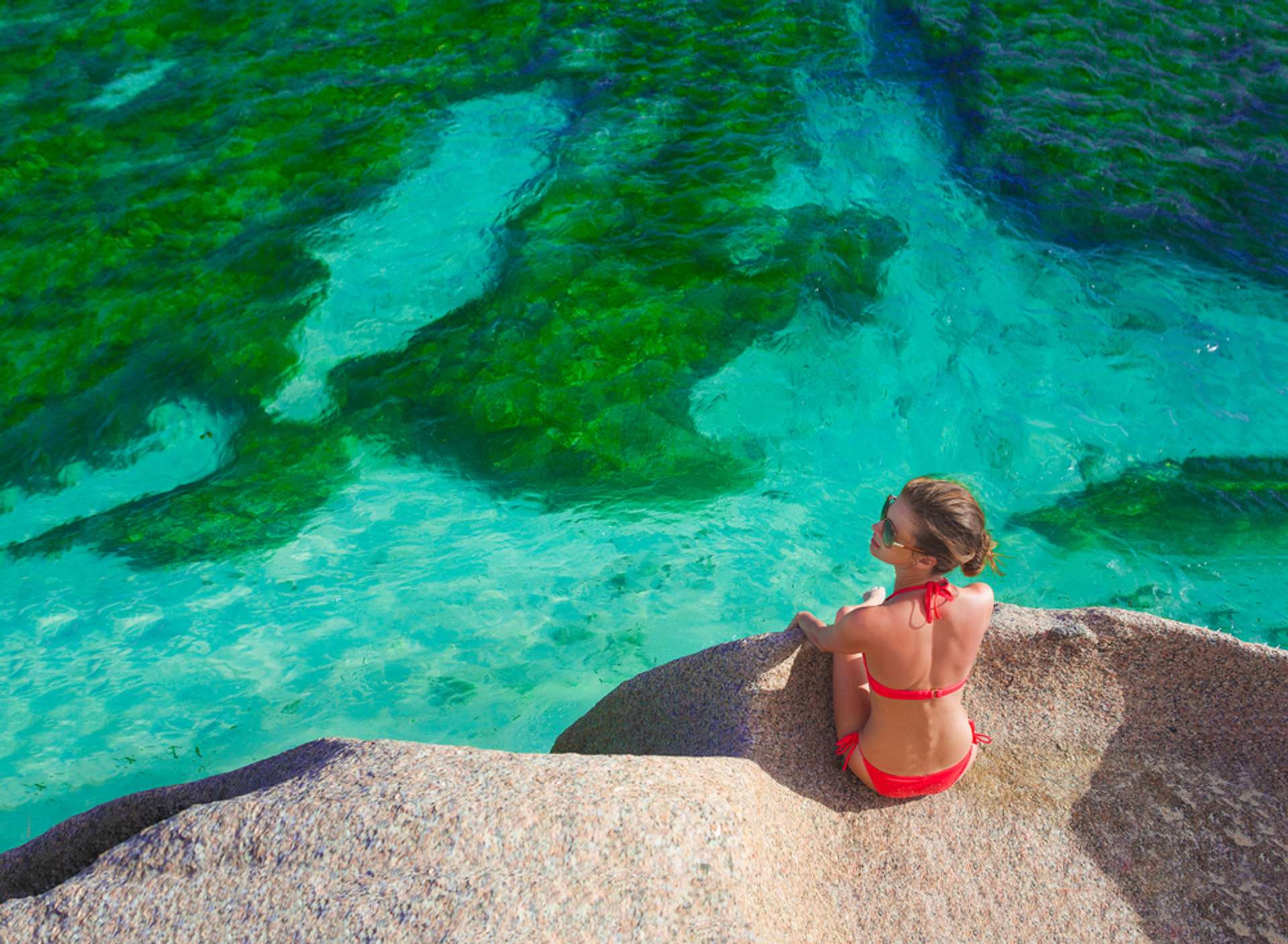 Seychellen La Digue vrouw zit op rotsen